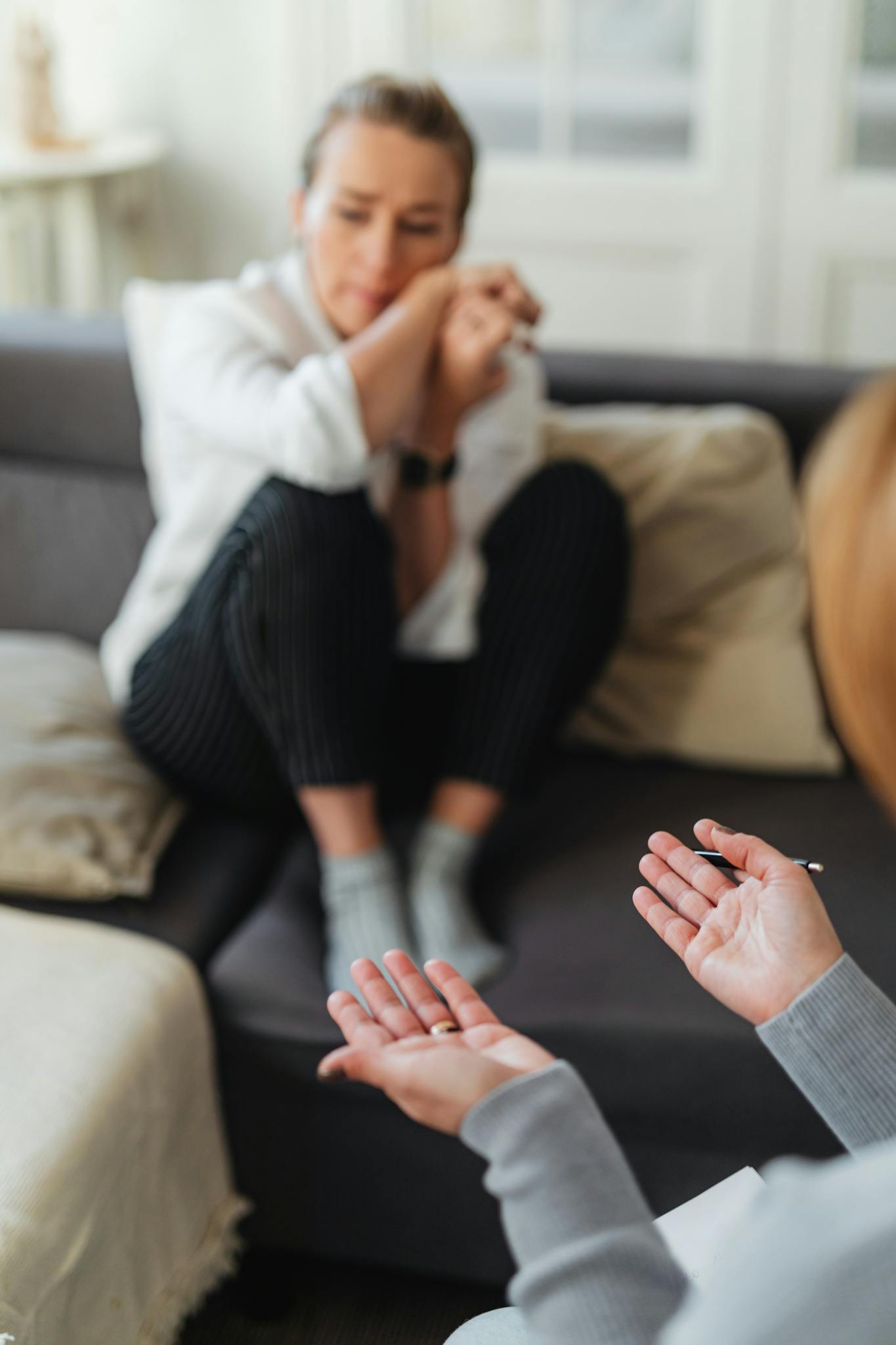 A woman in distress during a therapy session, showing emotional support and communication.