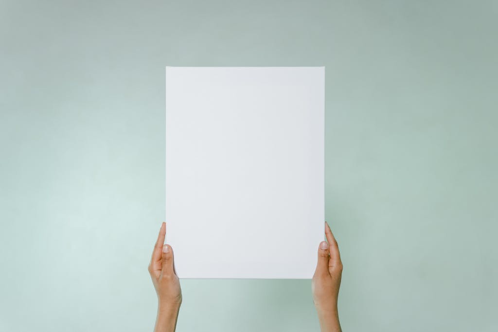 Simple blank canvas held hands on light green background with copy space.